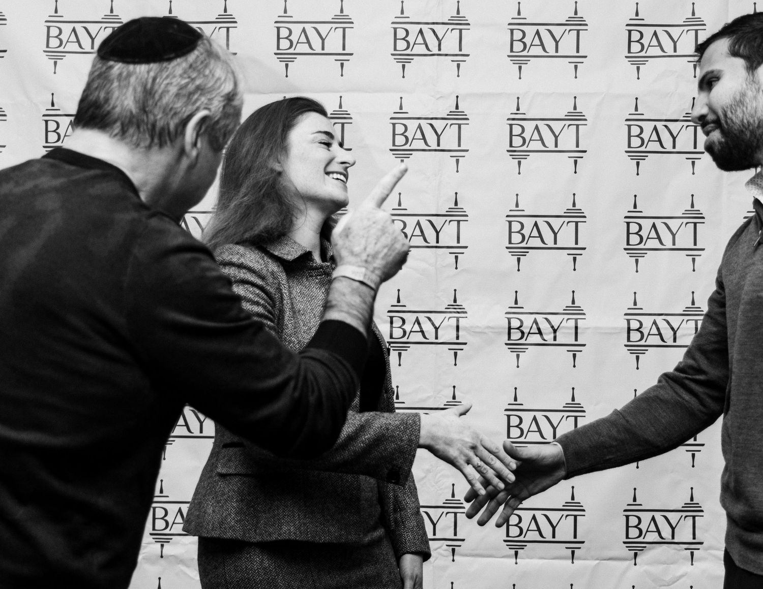 A series of black and white photos showing people interacting in front of a wall with repeating BAY1 text pattern.