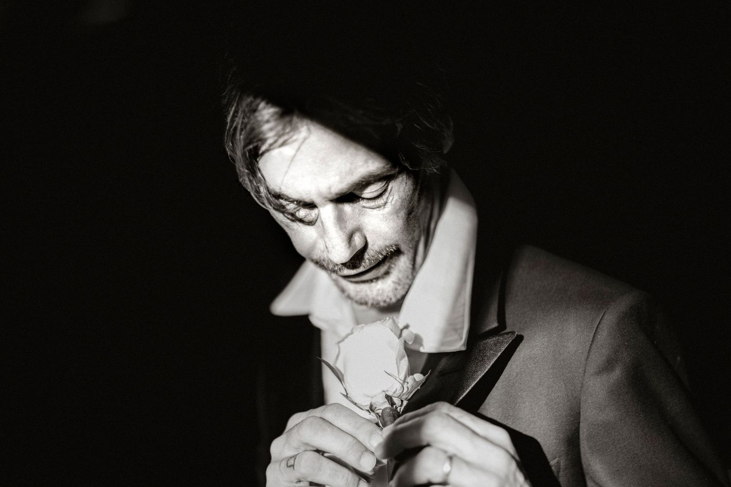 Black and white photo of someone smoking a cigarette in a dark moody setting.