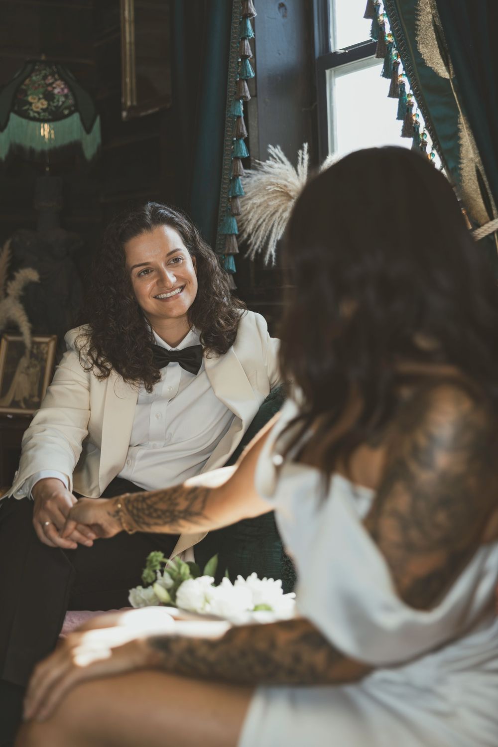 A couple shares an intimate moment while sitting together in a cozy, dimly lit interior setting.