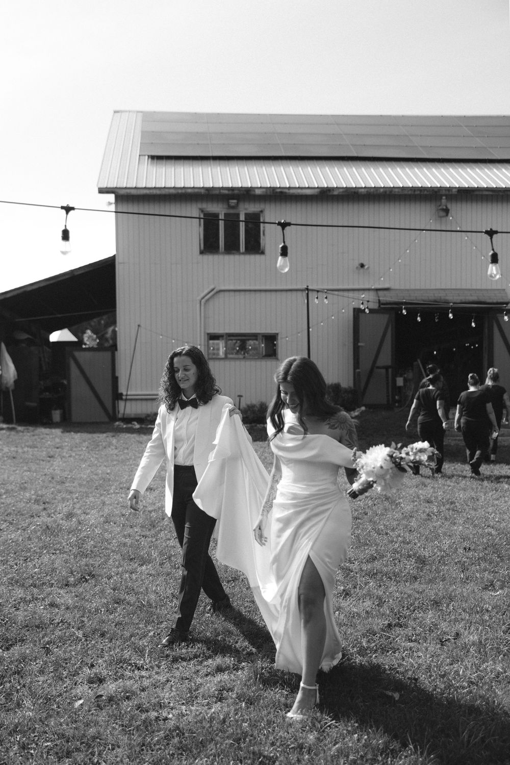 A black and white sequence of a bride's dress flowing in the wind as she spins and dances in a grassy field.