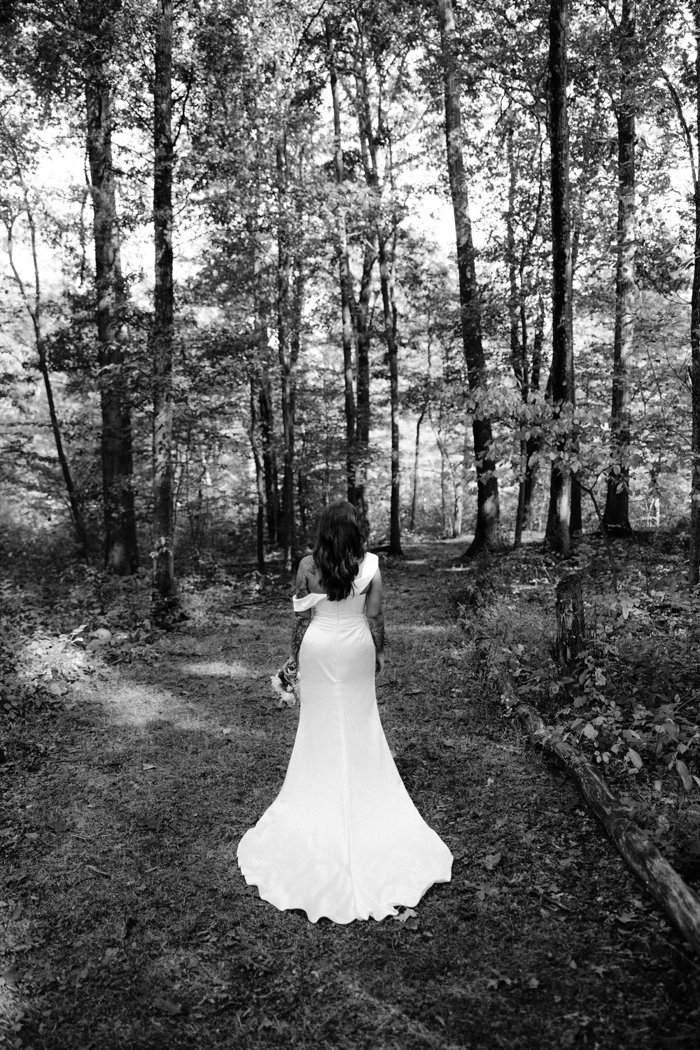 Black and white photos show a flowing white wedding dress displayed among trees in a forest setting.