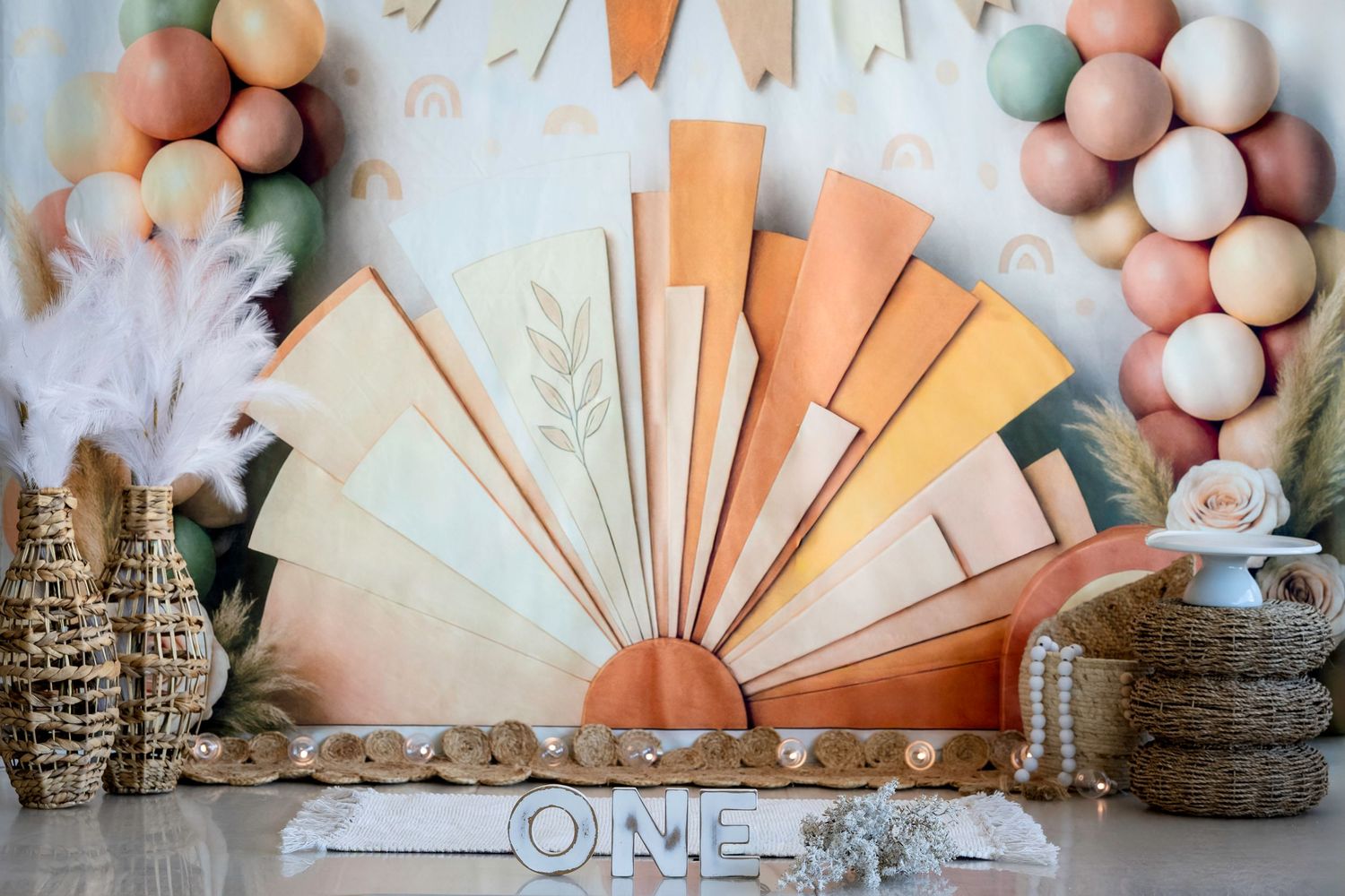 A boho-themed first birthday Smash & Splash setup with peach and pink decorations, balloons, and rustic accents.