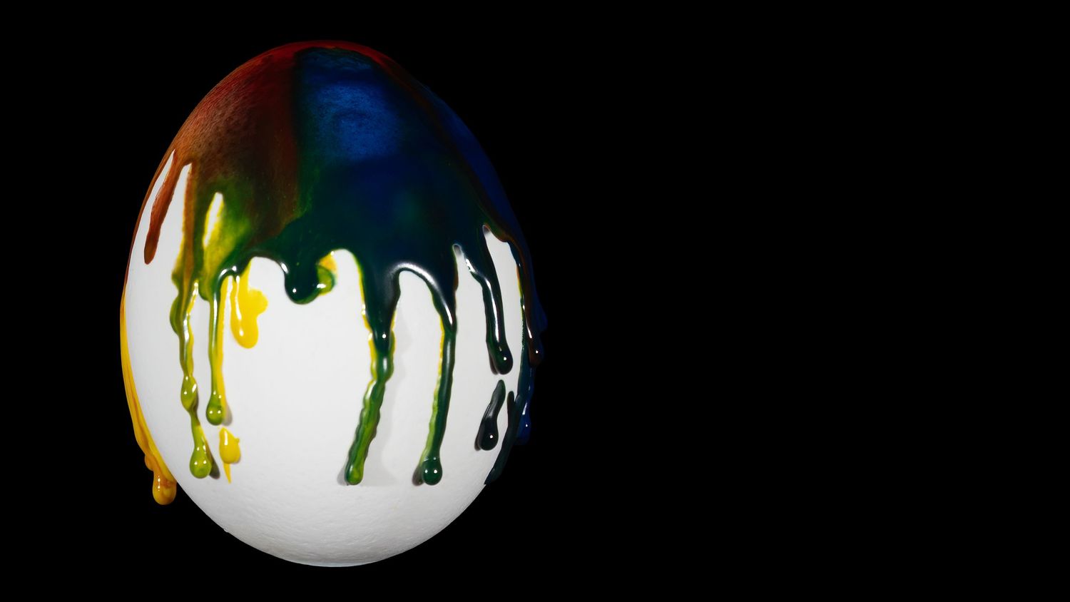 A row of six white spheres with colorful paint drips in yellow, green, and black flowing down their surfaces.