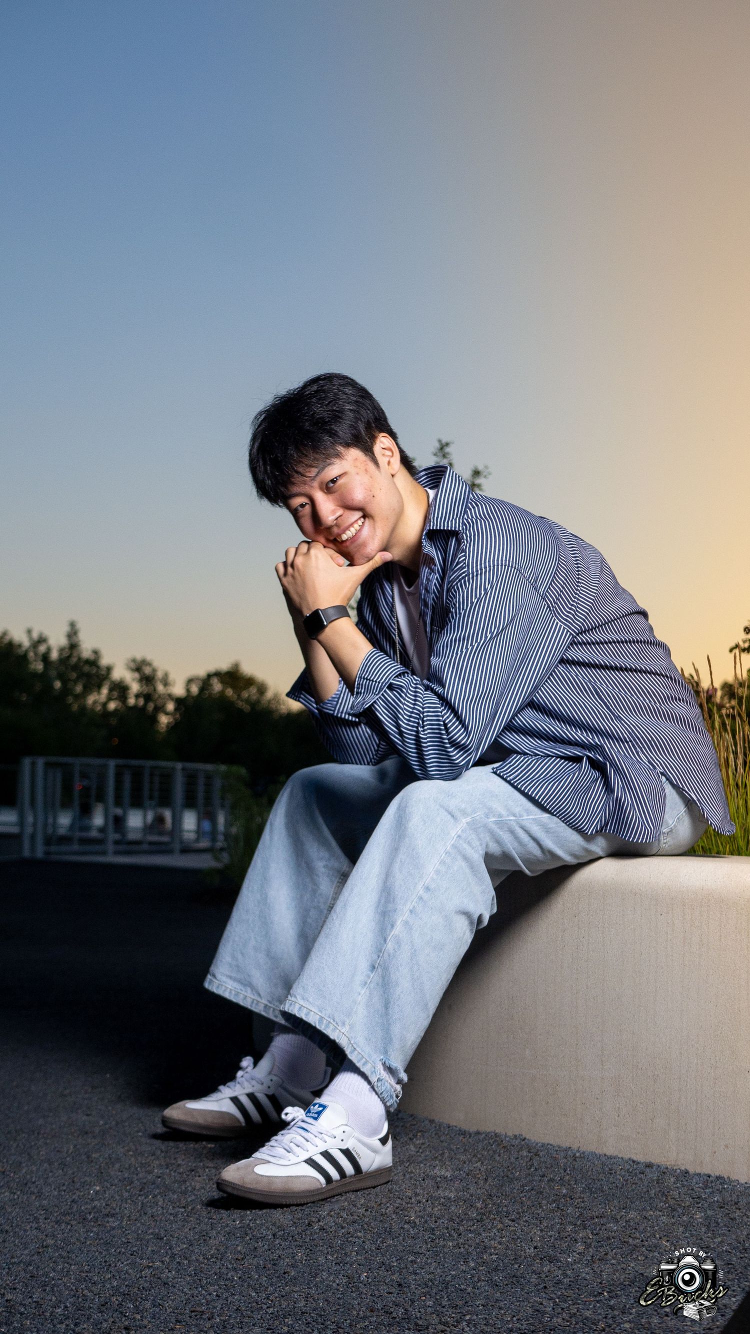 Sunset portrait of person in striped shirt sitting casually outdoors.