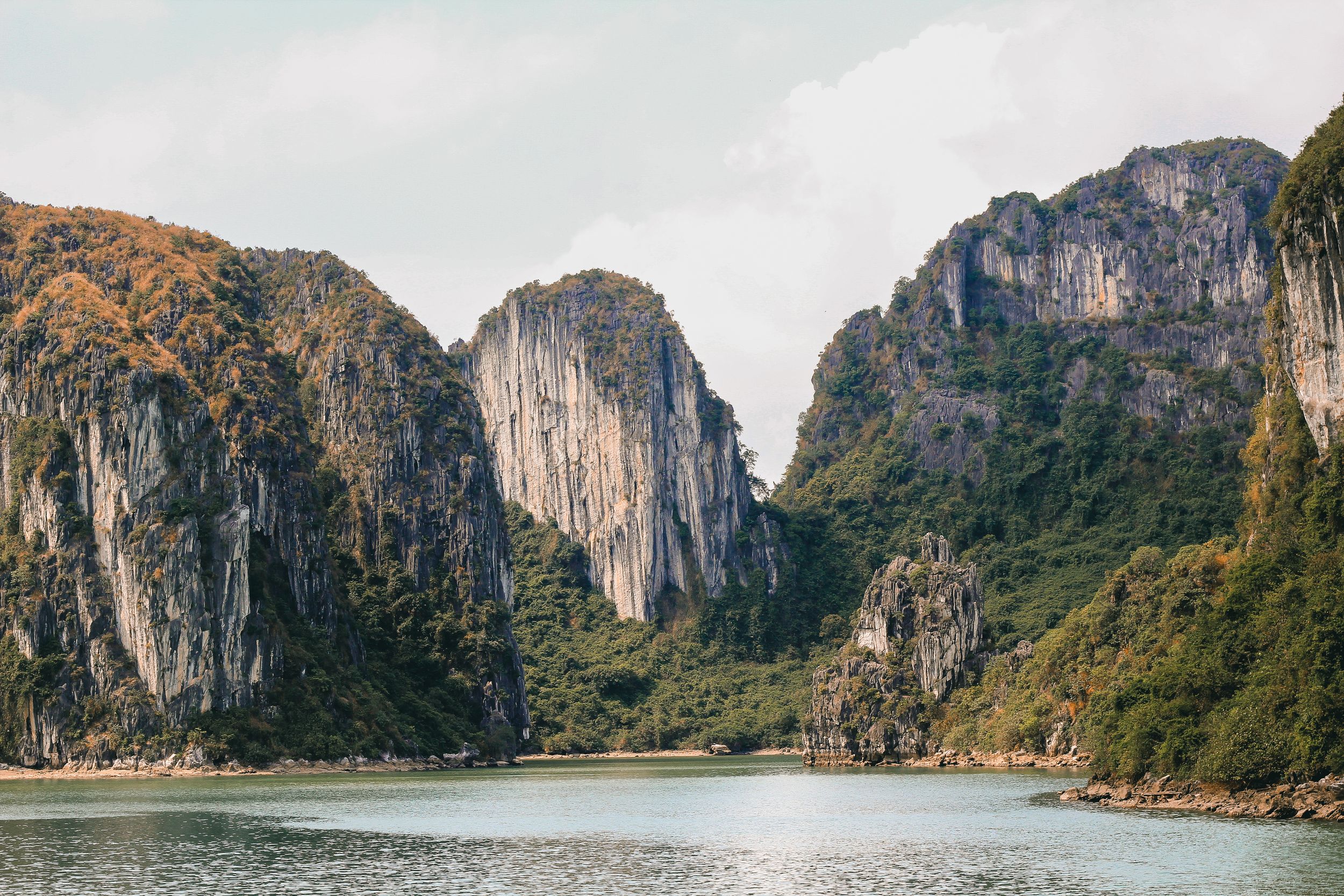 Majestic canyon walls rise above a peaceful river flowing between steep mountain cliffs.