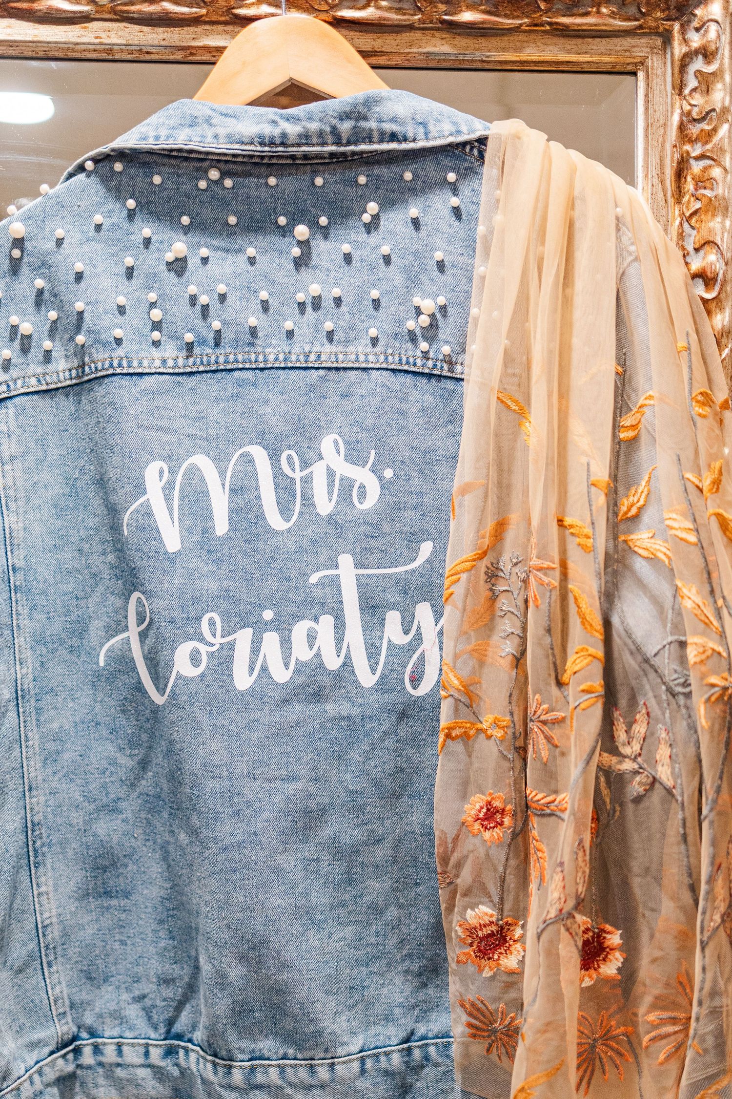 Personalized denim jacket with 'Mrs' script and pearl embellishments for bride.