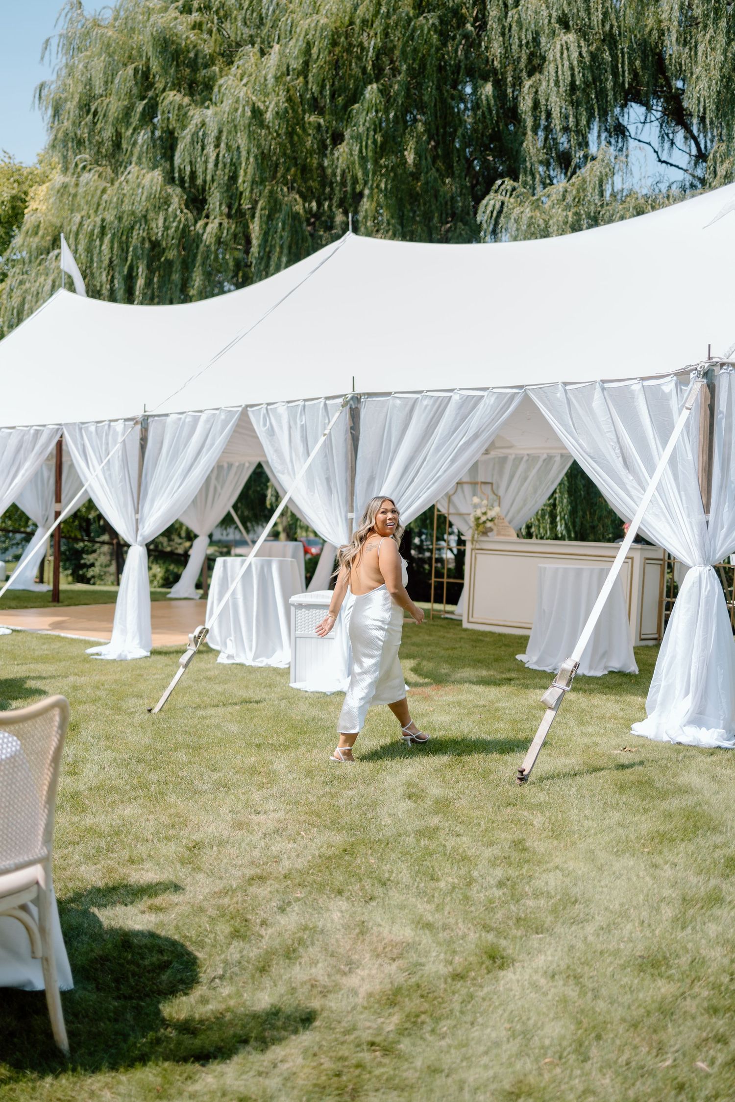 Elegant white wedding tent with flowing drapes in outdoor garden setting.