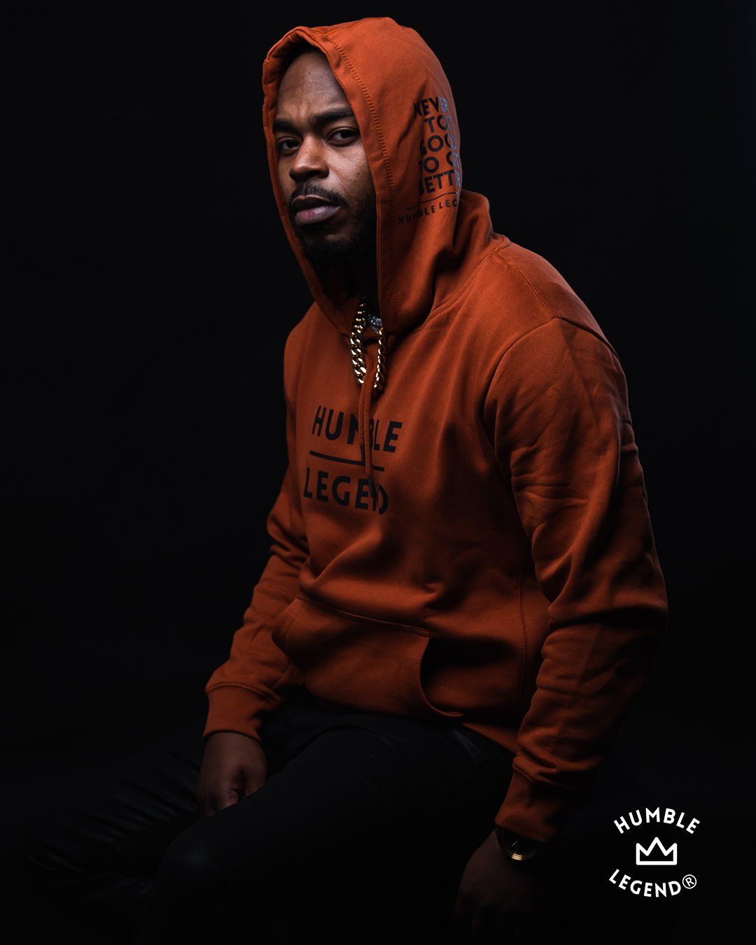 Portrait of person wearing orange hoodie against dark background.
