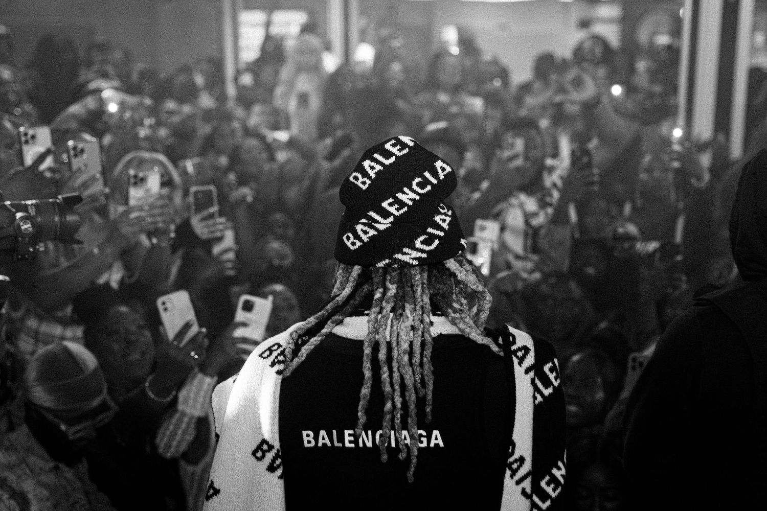 Black and white crowd photo with person wearing Balenciaga clothing in focus.