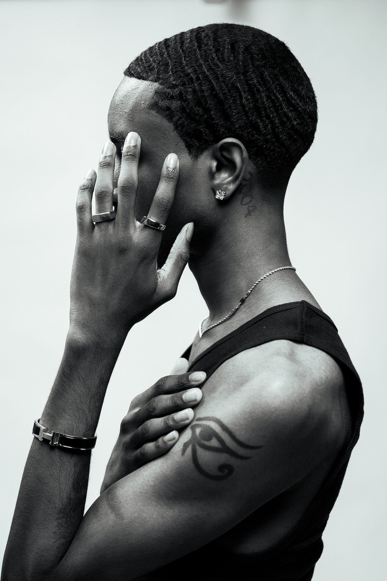 Artistic black and white portrait showing jewelry and tattoo details in minimalist style.