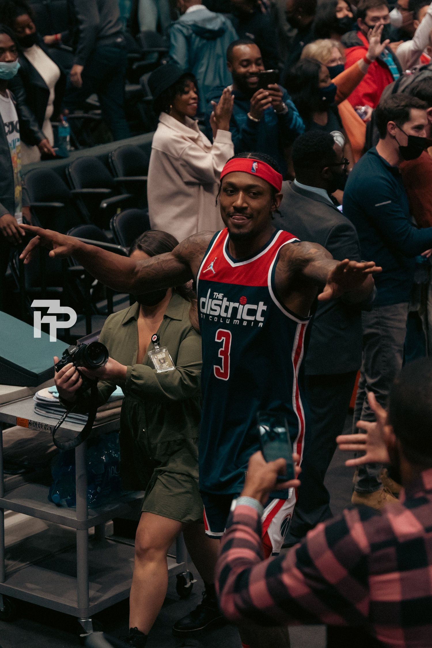 Basketball fan in Washington jersey celebrates enthusiastically among crowd at sports event.