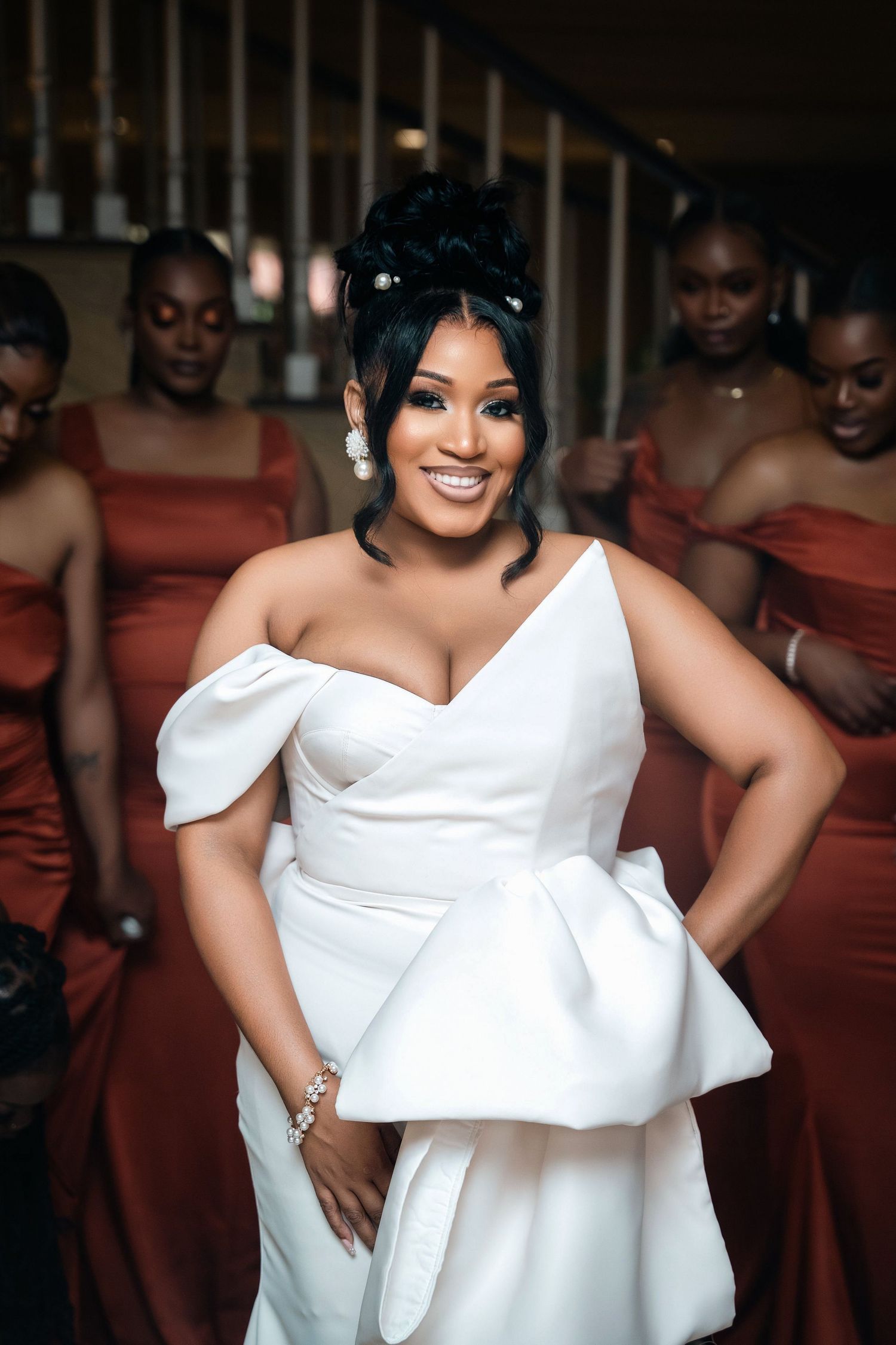 A bridal celebration featuring a bride in white and bridesmaids in rust-colored dresses.