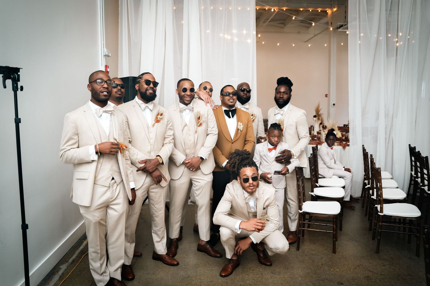 Group photo of wedding party members dressed in cream and tan colored suits.