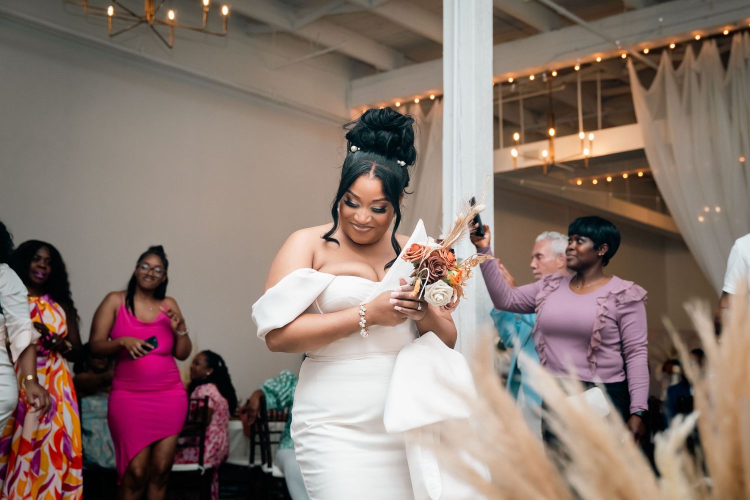 A bride in white dress checking her phone during wedding reception.