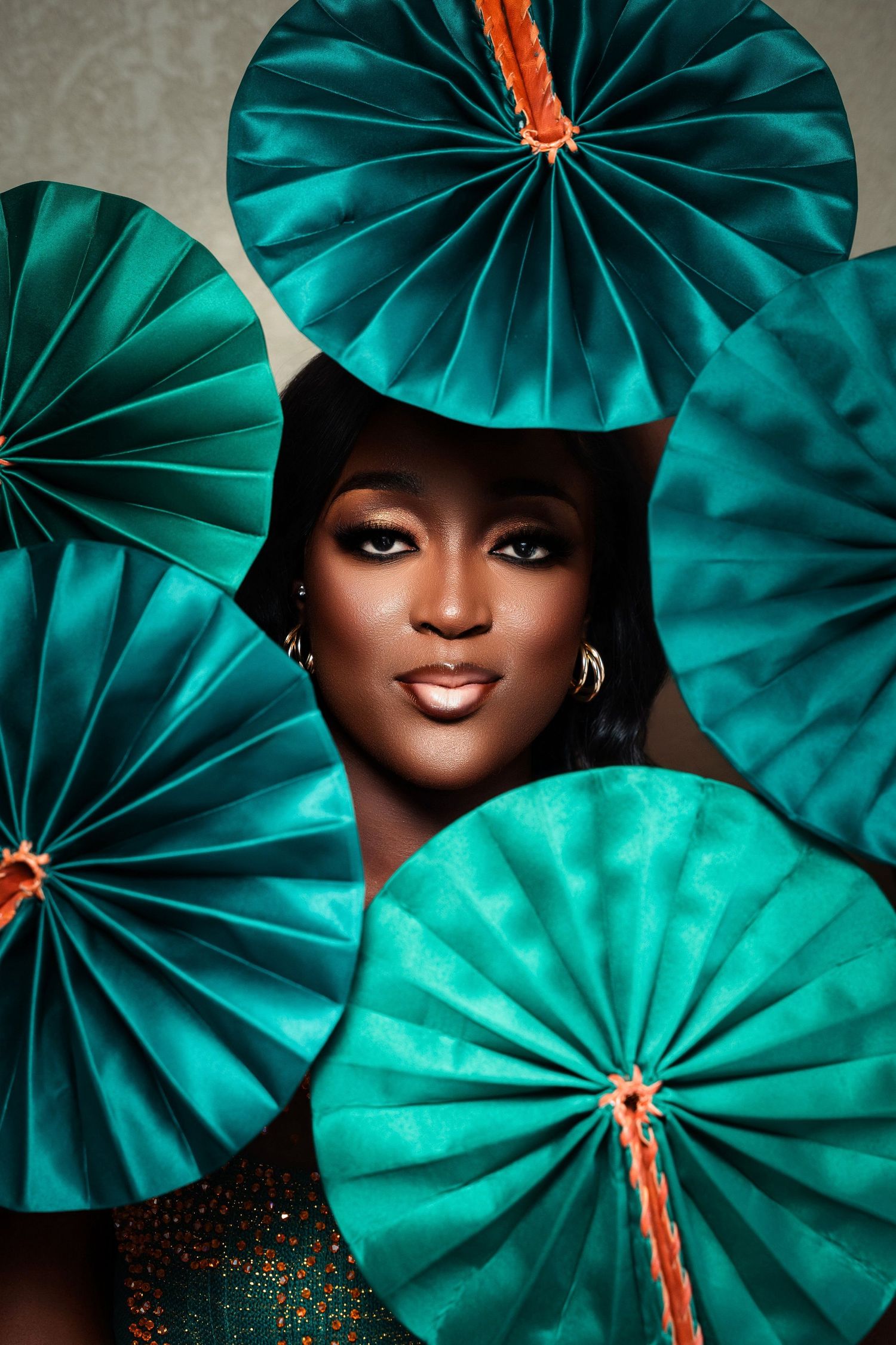 Fashion portrait with emerald green paper fans creating a dramatic backdrop.
