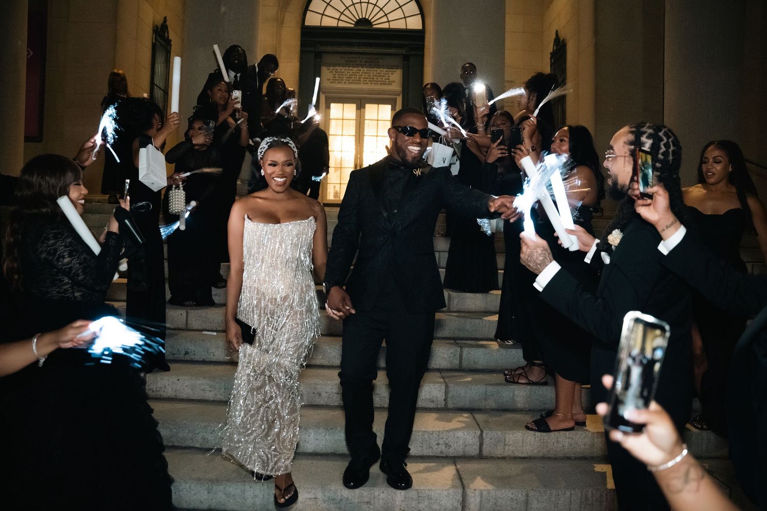 Wedding guests wave glowing foam sticks during an evening wedding reception celebration.