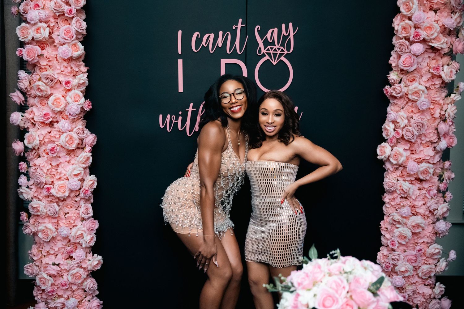 Two women in sequined dresses posing together at a bridal celebration.