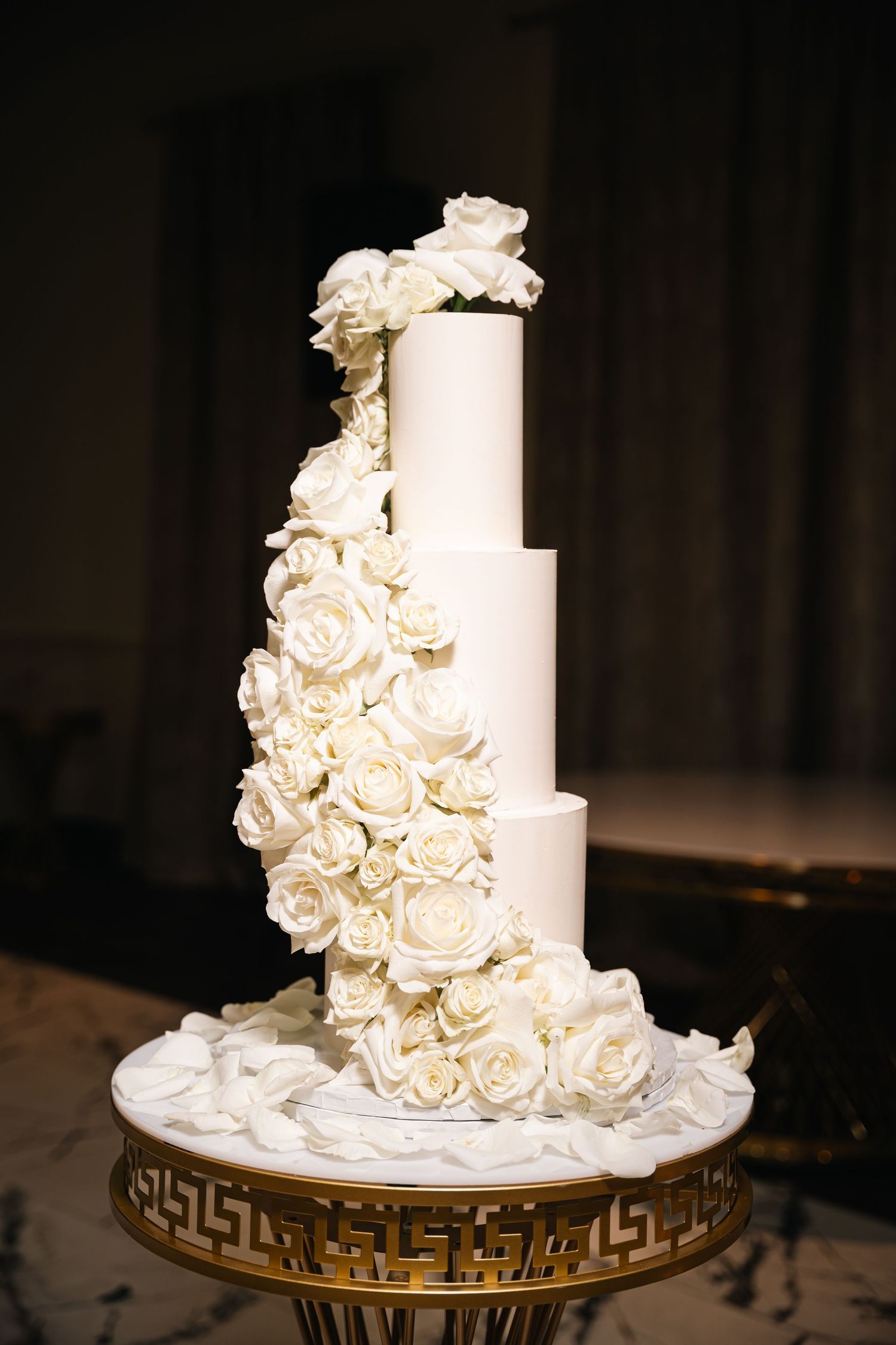 Set of four photos showing a traditional white wedding cake with cascading cream roses on a gold metallic base.
