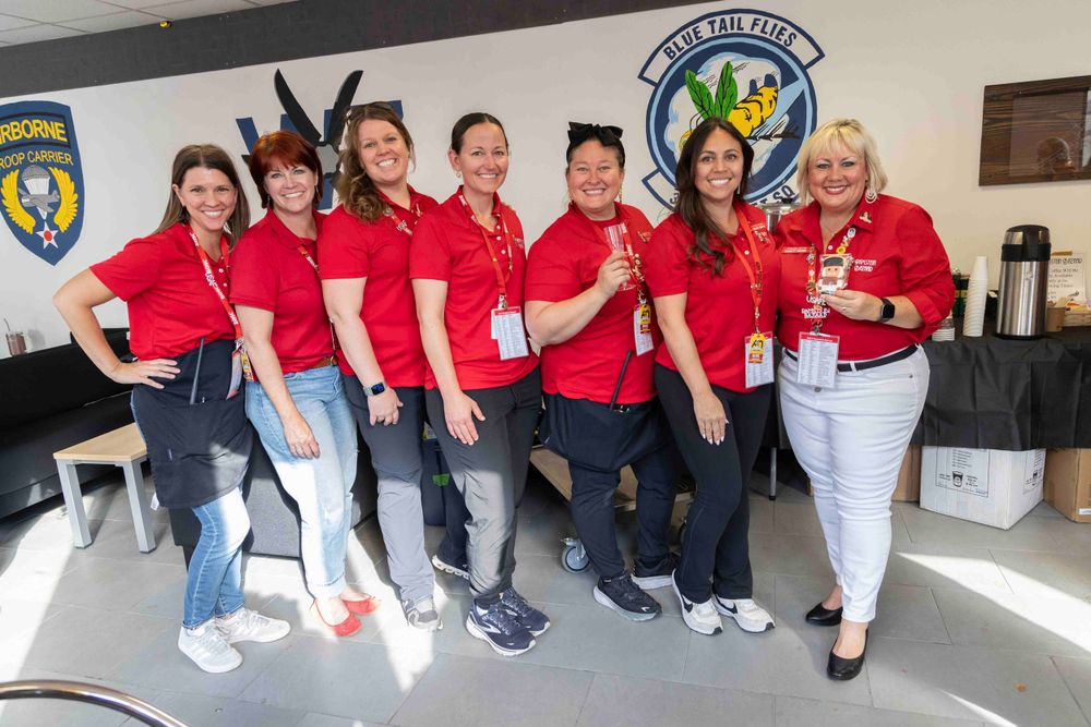 Group of staff members in red uniforms posing together at an event.