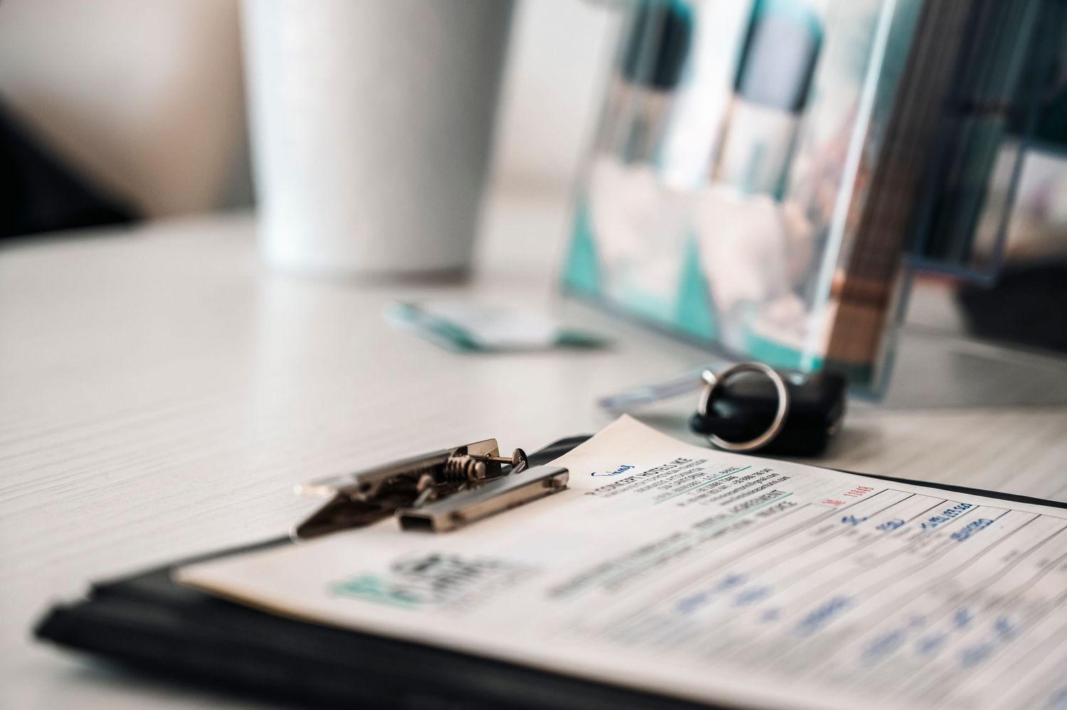 Medical chart or clipboard with paperwork and pen laying on white desk.