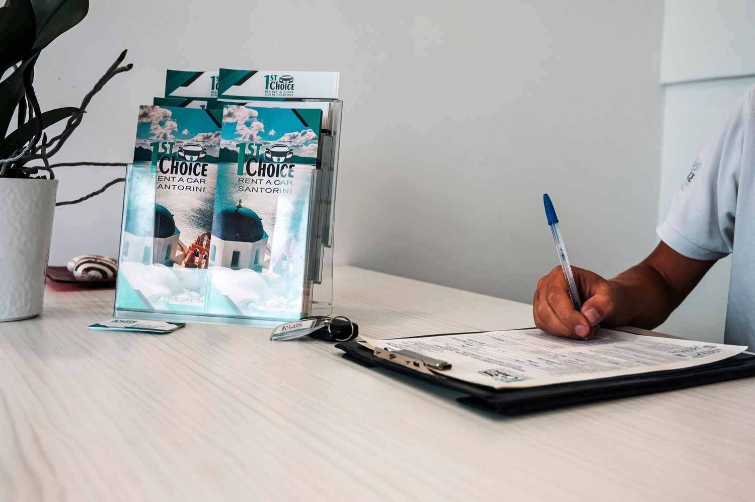 Hand writing on clipboard with medical documents and folder on white desk.