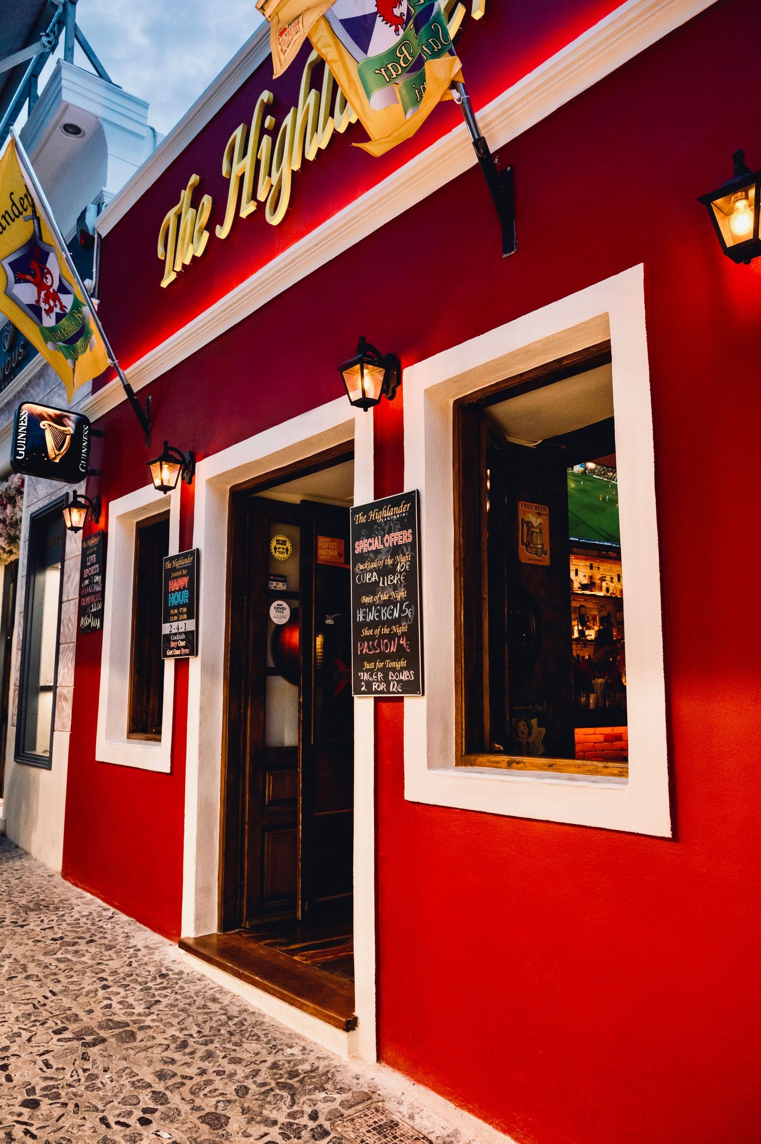 Bright red exterior of The Highlander pub with white trim and lantern lighting.