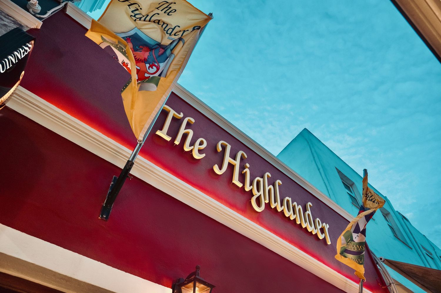 The Highlander pub sign mounted on a red building exterior.