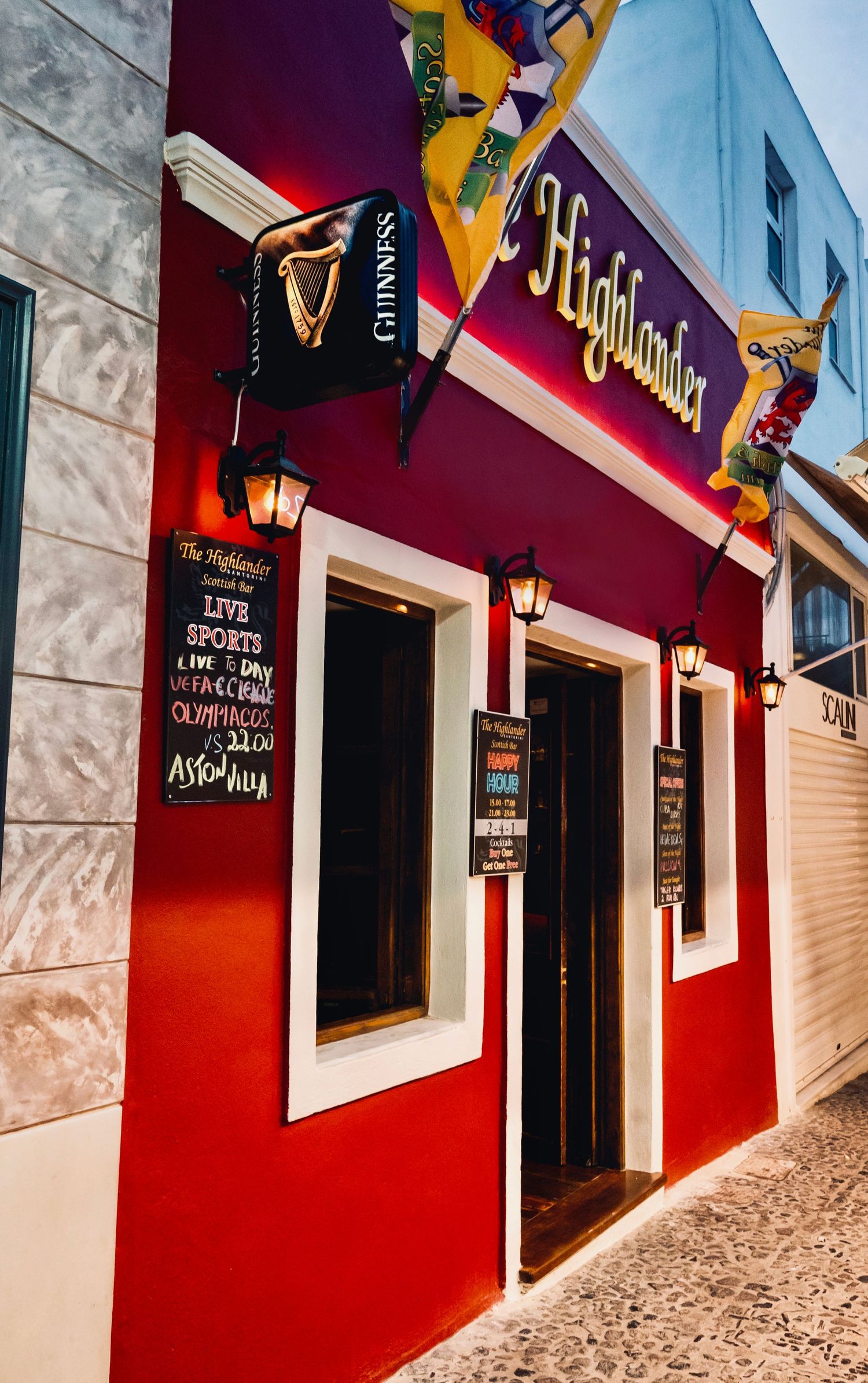 Red exterior facade of The Highlander pub with Guinness signage and menu boards.