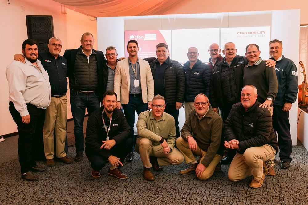 Group of smiling business professionals posing together at a corporate conference event indoors.