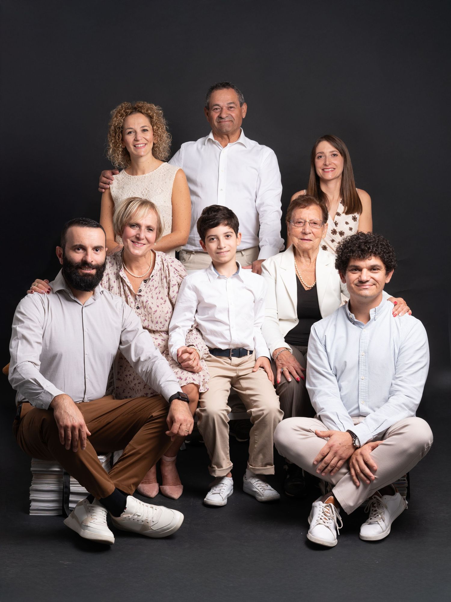 A series of casual family portraits on a dark background with everyone coordinated in white and neutral colored clothing.