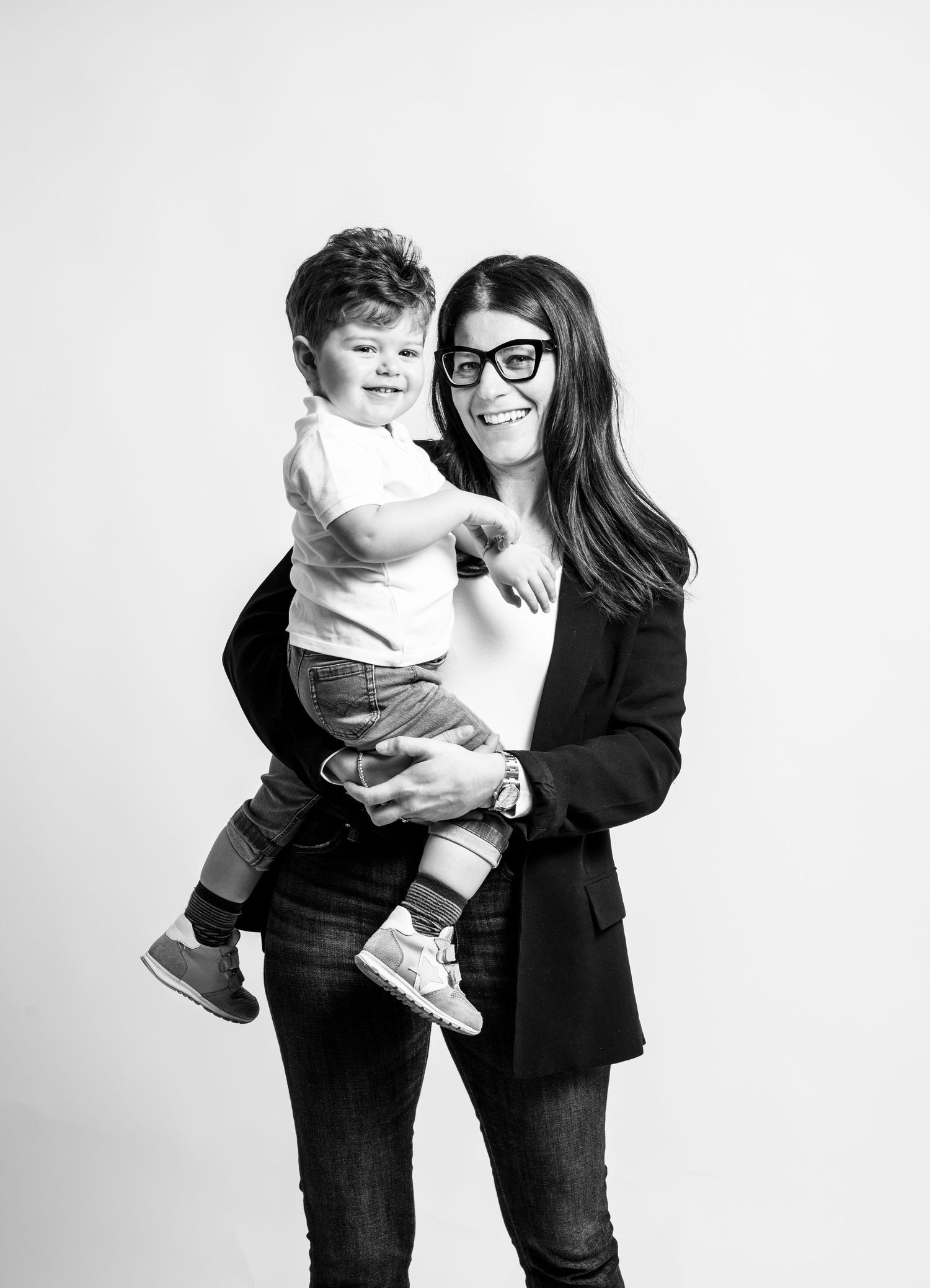 A black and white photo series showing playful interaction between two people in casual attire against a white backdrop.