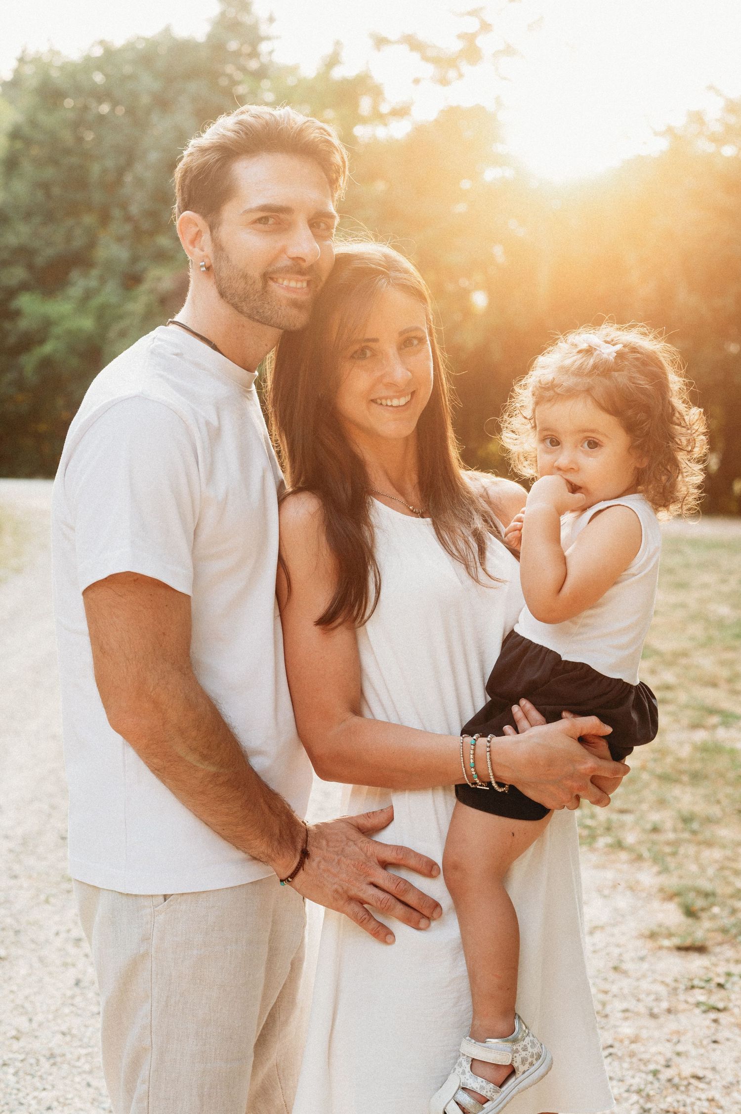 Family enjoying golden hour photoshoot outdoors in matching white outfits during sunset.