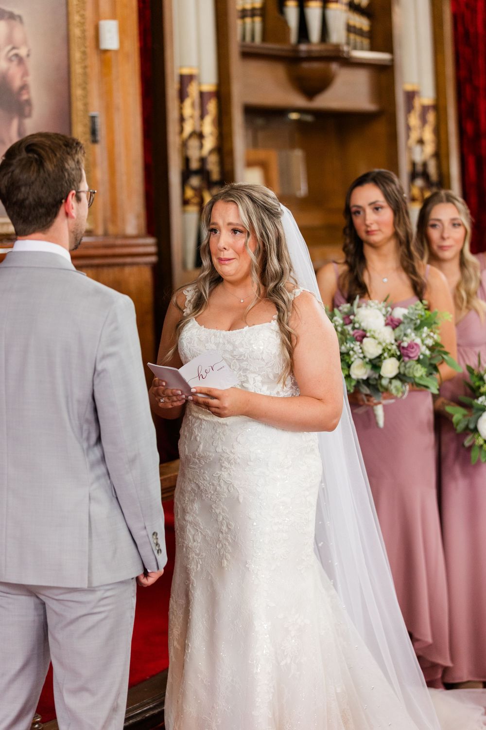 Wedding party members in pink dresses and gray suits gather during an emotional first look ceremony.