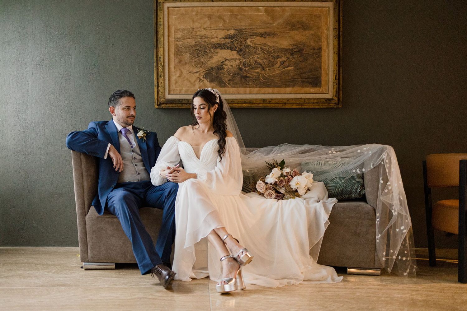 Elegant wedding portraits in a sophisticated room with dark walls and classic artwork.
