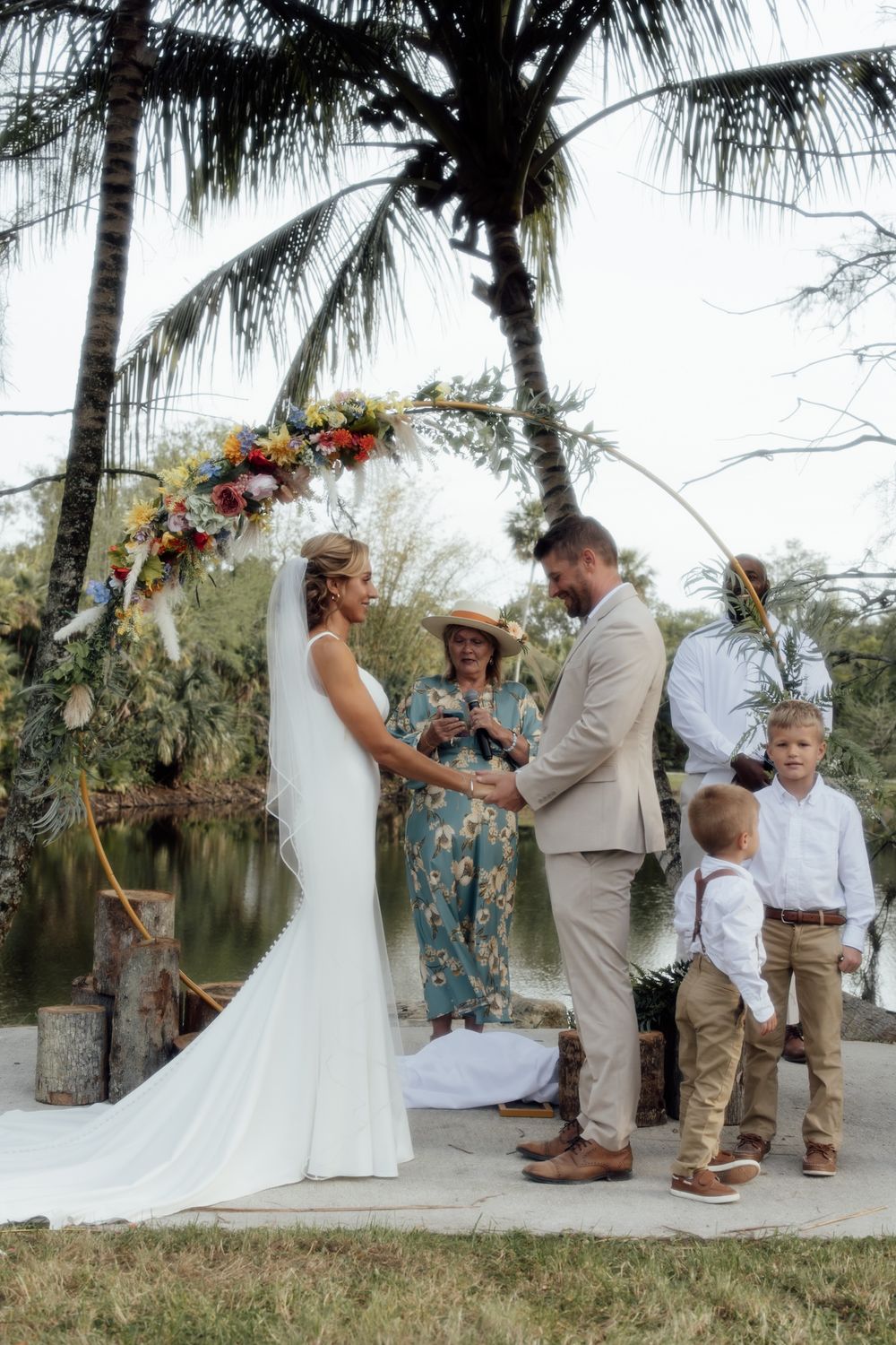 A romantic lakeside wedding ceremony with rustic details and palm trees framing an intimate gathering of loved ones.
