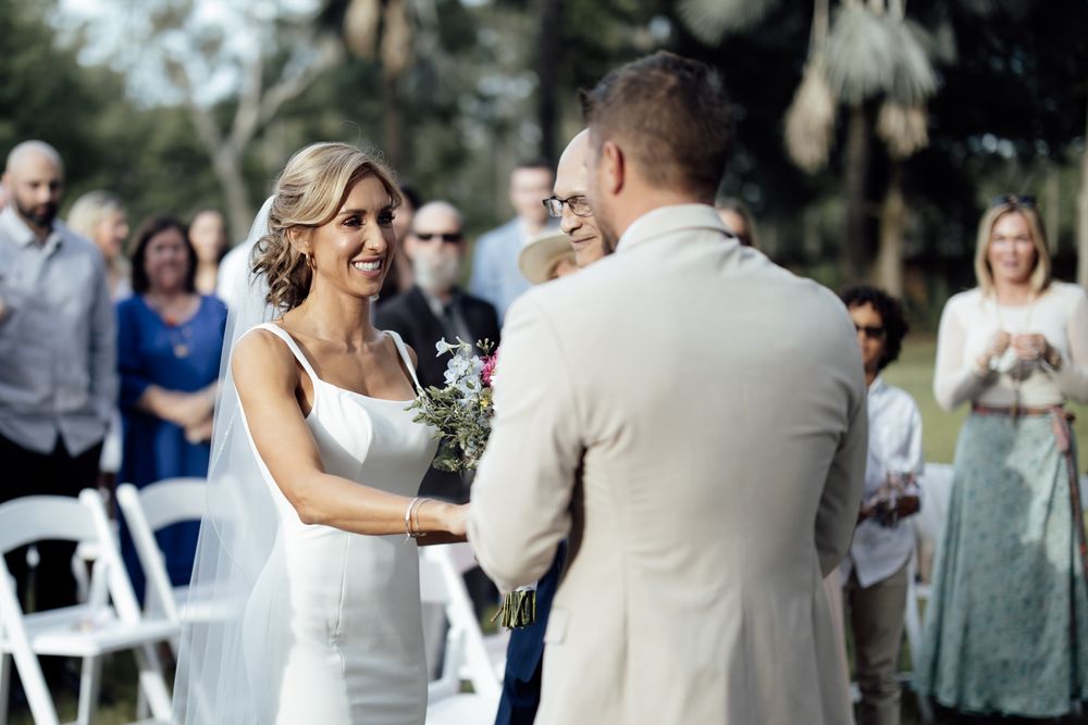 Wedding celebration with guests dancing on a tree-lined outdoor venue.