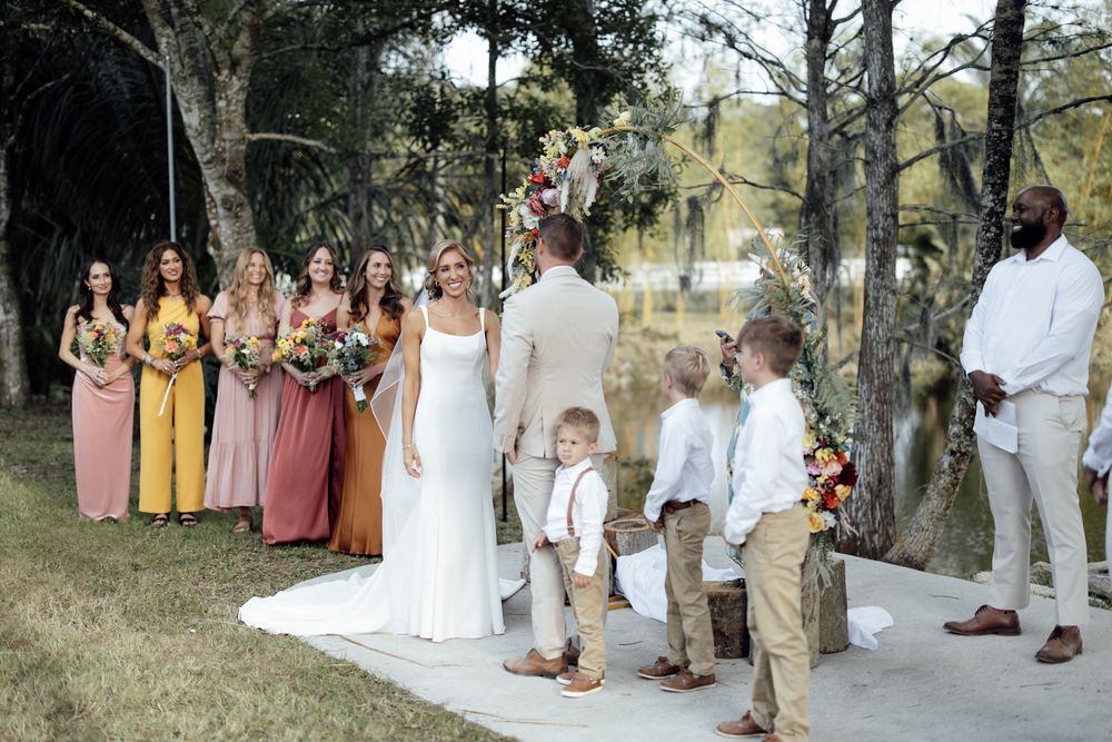Wedding party members gather outdoors for group photos in coordinated white and neutral attire.