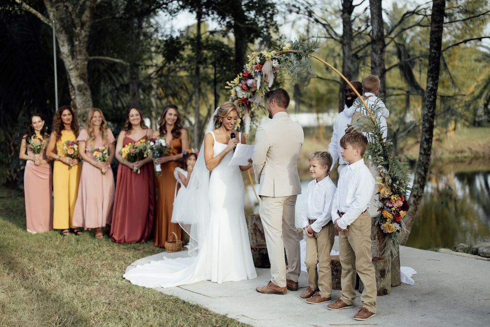 Wedding party gathers along a scenic path with bridesmaids in pink and burgundy dresses.