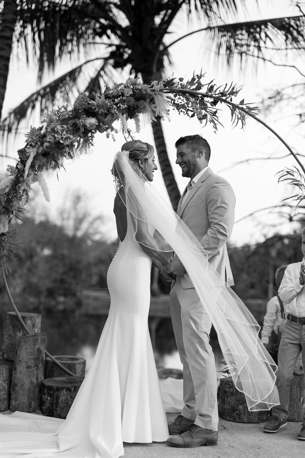 Black and white wedding photos show tender moments between a couple under palm trees.