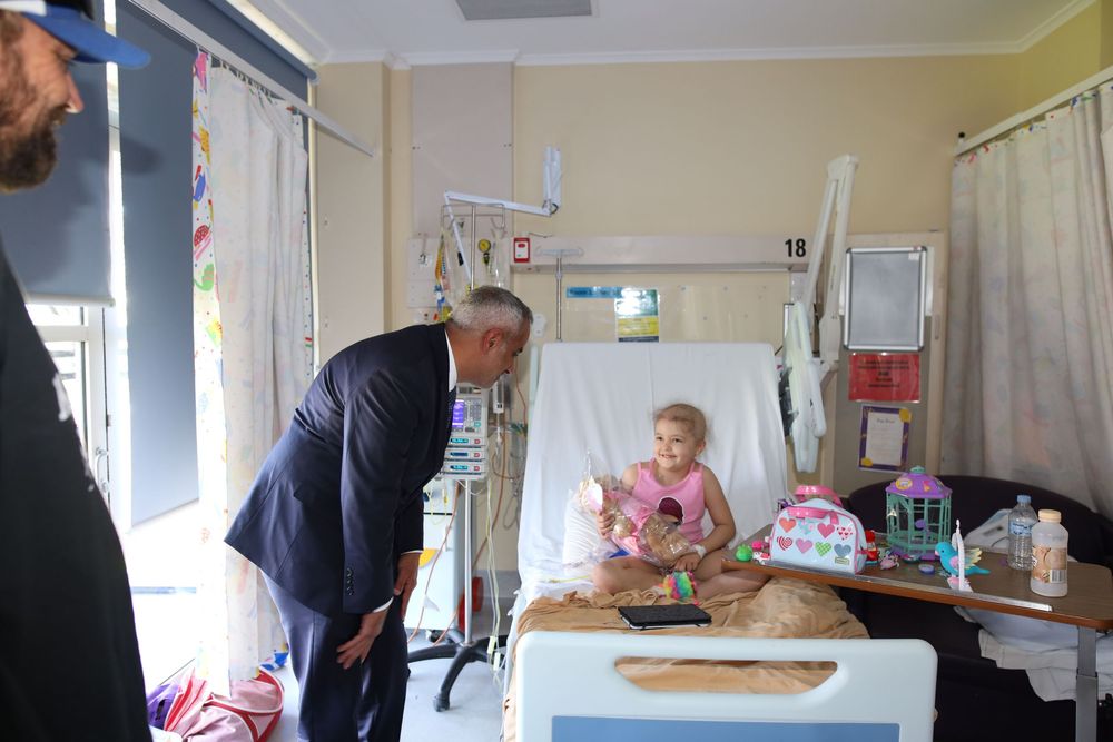 UAE Official visiting a hospital, speaking with a young suvivor at their bed.