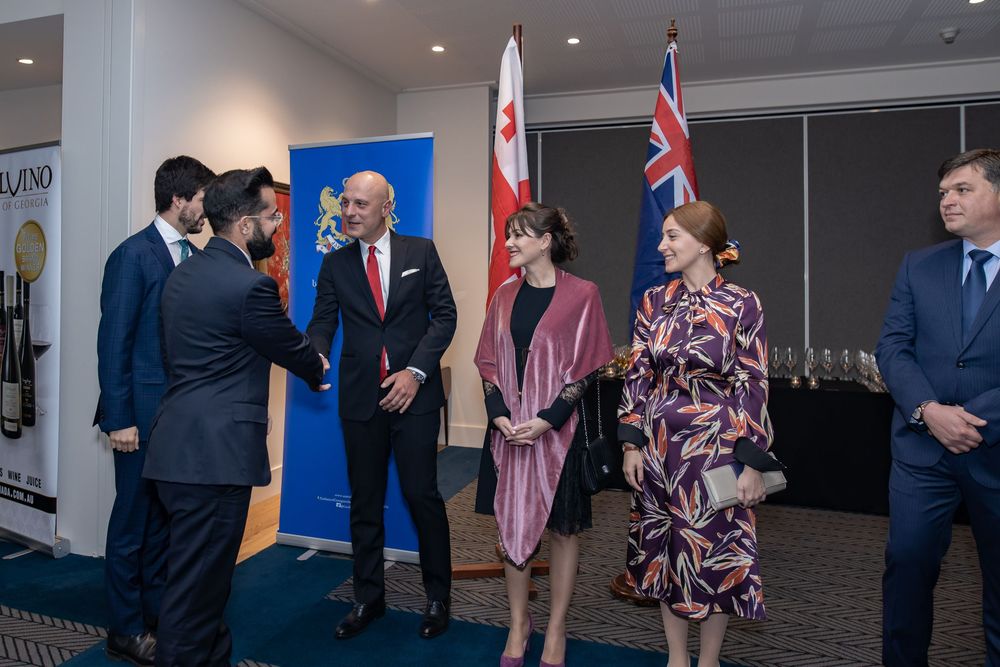 Signing ceremony with officials at a table, Australian and partner nation flags behind.