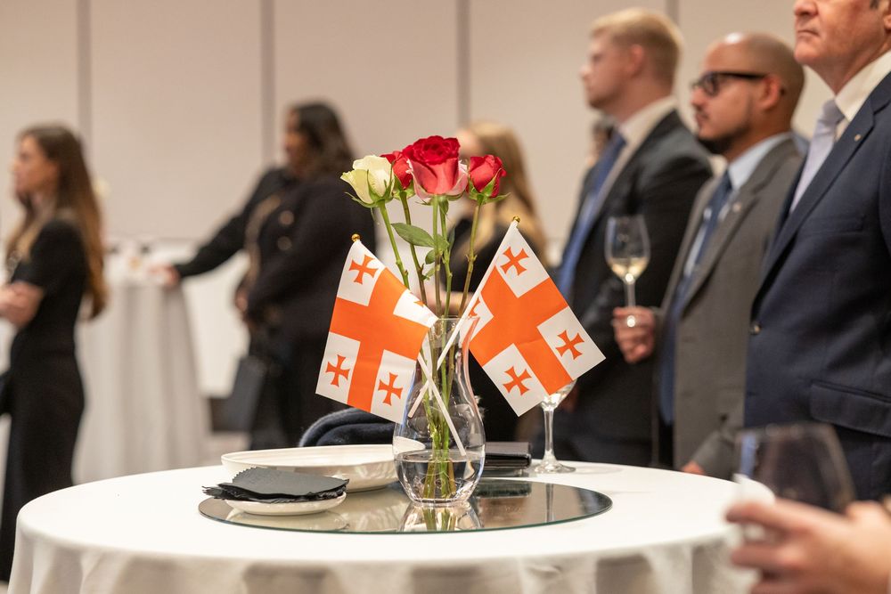 Embassy reception cocktail table with national flags and flowers as guests network.