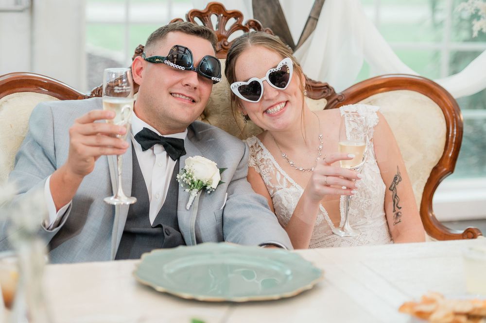 Elegant reception table settings at an outdoor wedding with champagne glasses and floral centerpieces.