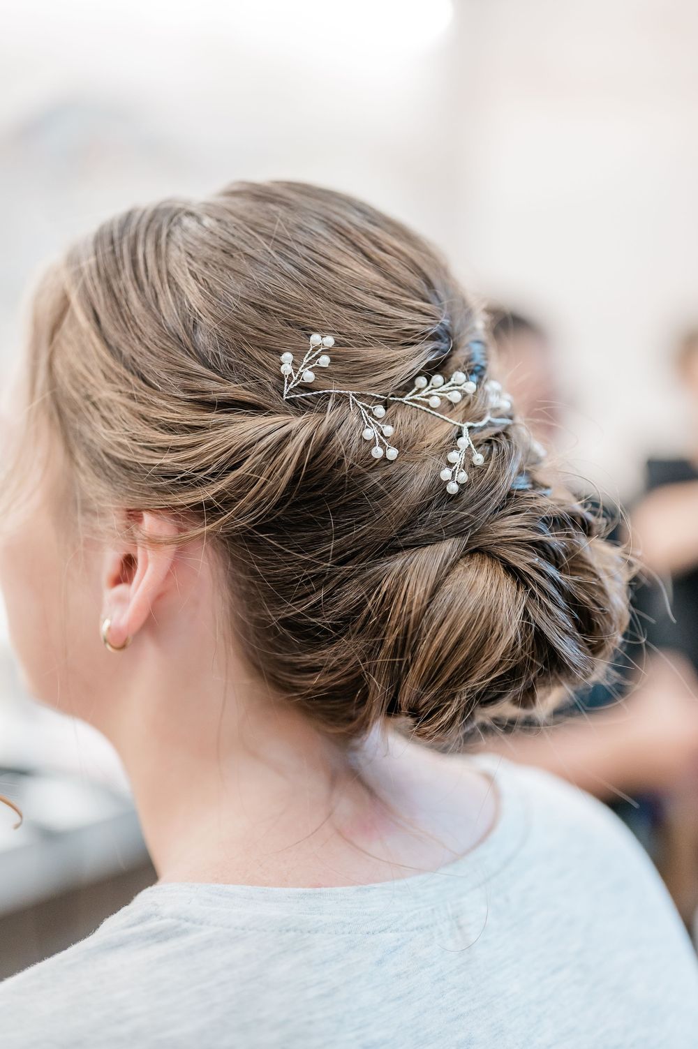 Delicate bridal hairstyle with pearl and crystal hair accessories woven into an updo.