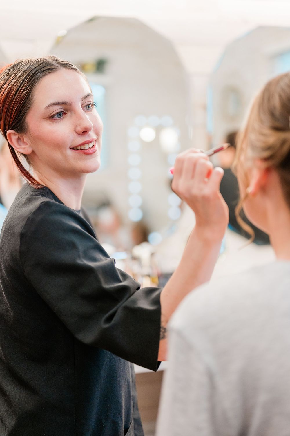 Stylists in black uniforms work on clients' hair in a modern salon setting.