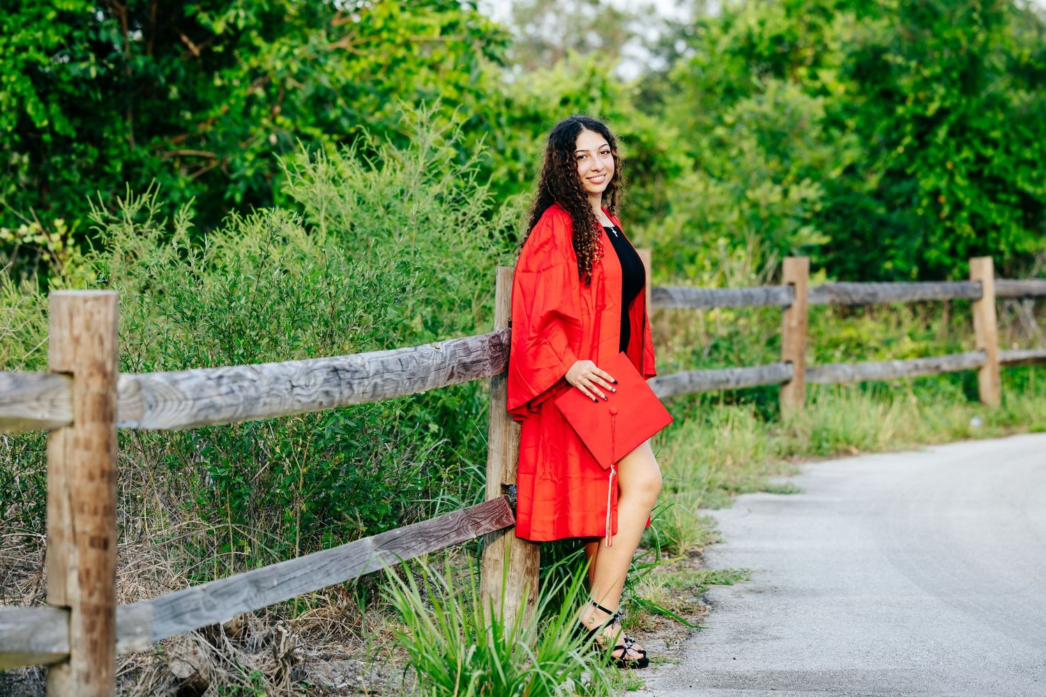 A scenic path winds through lush green foliage with wooden fence posts along the sides.