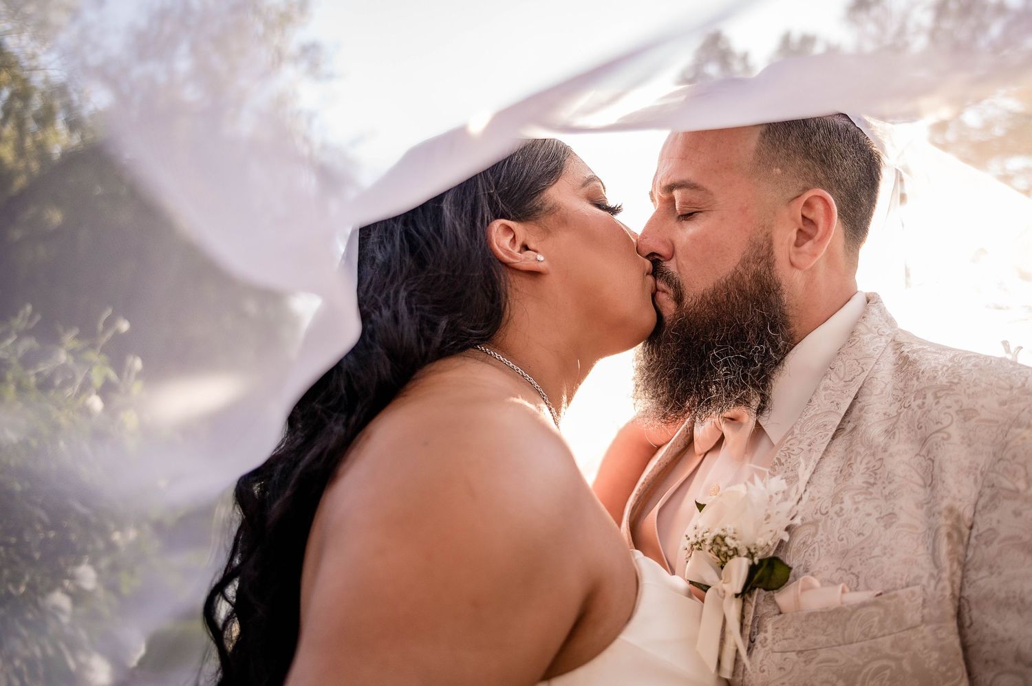 Intimate outdoor wedding portrait with golden sunlight filtering through trees.
