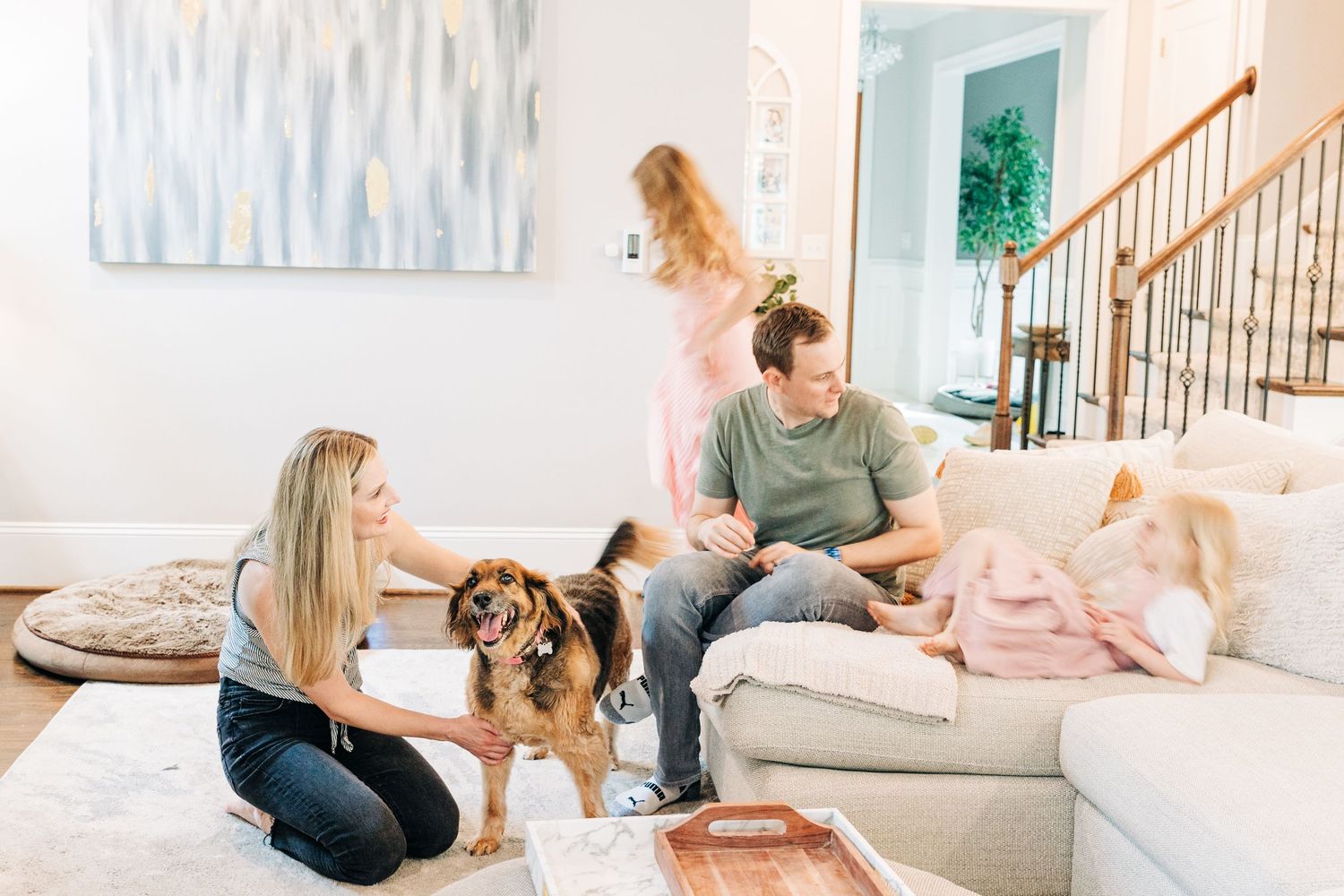 Family relaxes together in bright living room with their German Shepherd mix dog on cozy couch for Charlotte family photo session.