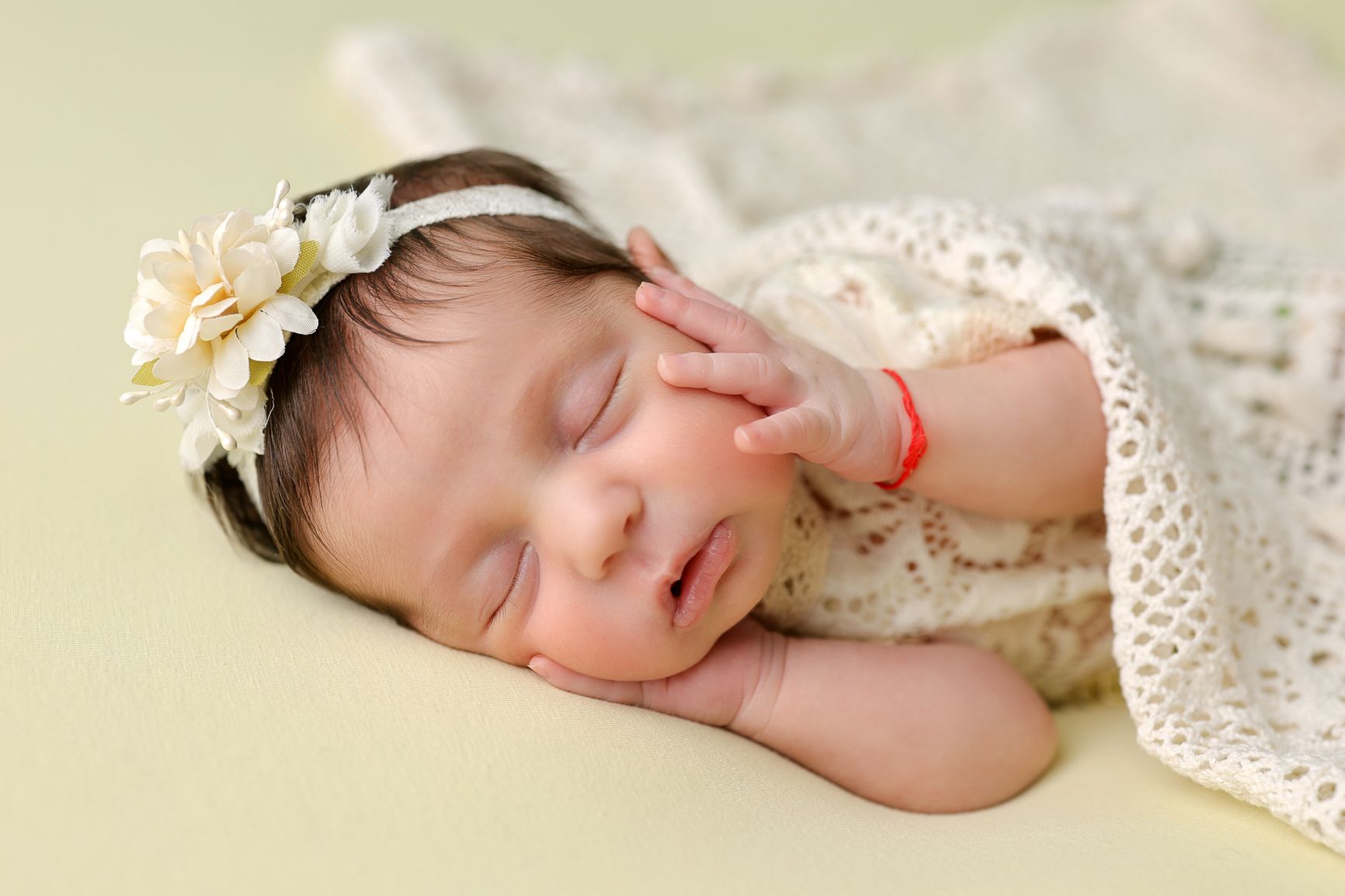Peaceful newborn sleeping on delicate lace backdrop in soft natural lighting.