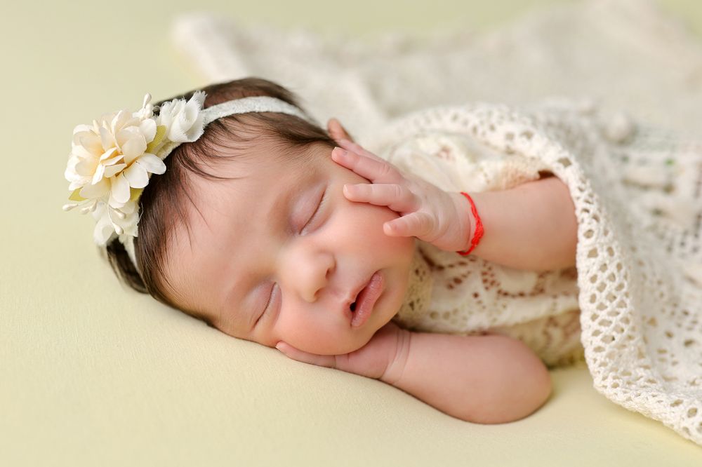 Peaceful newborn sleeping on delicate lace backdrop in soft natural lighting.